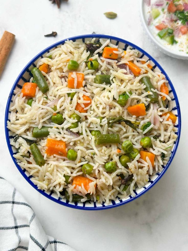 “Vegetable pulao with carrots, beans and peas served in a blue bowl”